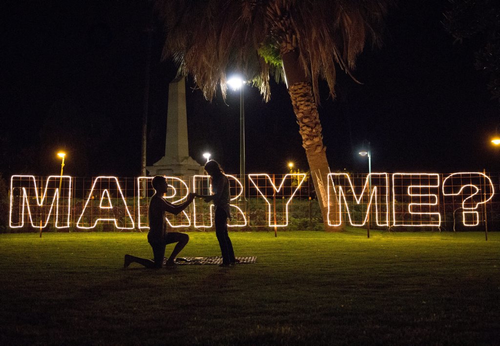 Luke Hine goes down on one knee to propose to girlfriend Katelyn Shearing in front of the sign he constructed at Queens Park. Luke Hine goes down on one knee to propose to girlfriend Katelyn Shearing in front of the sign he constructed at Queens Park.
